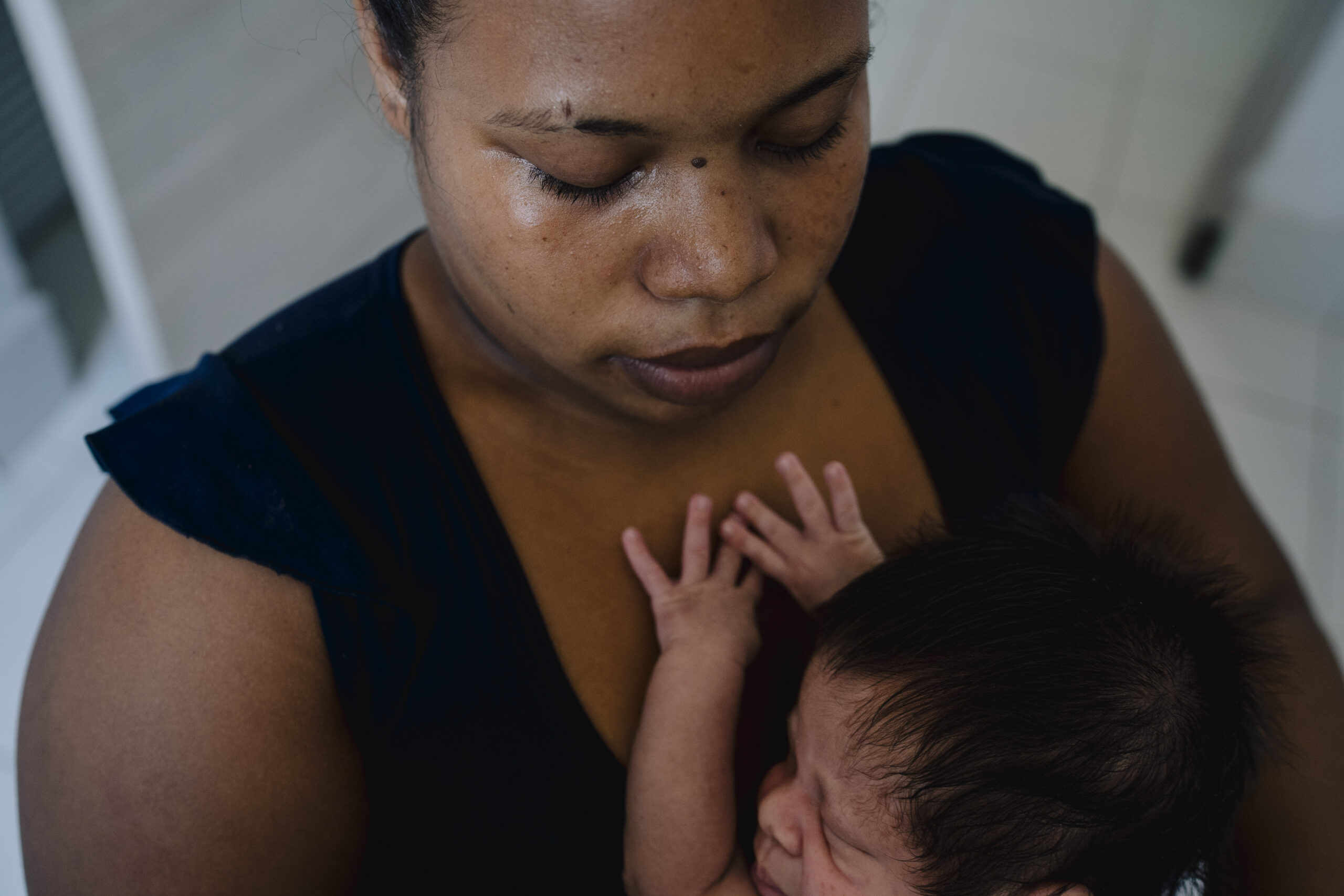 A woman holds her newborn close, looking down at the baby