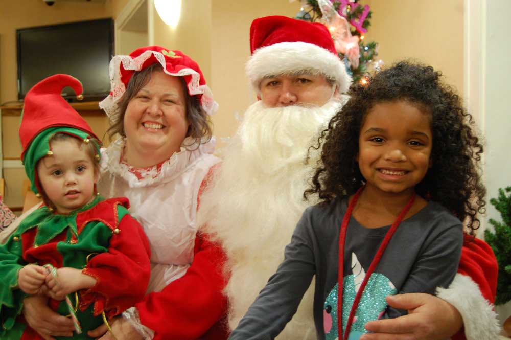 Chilren sitting on the laps of Santa and Mrs. Klaus