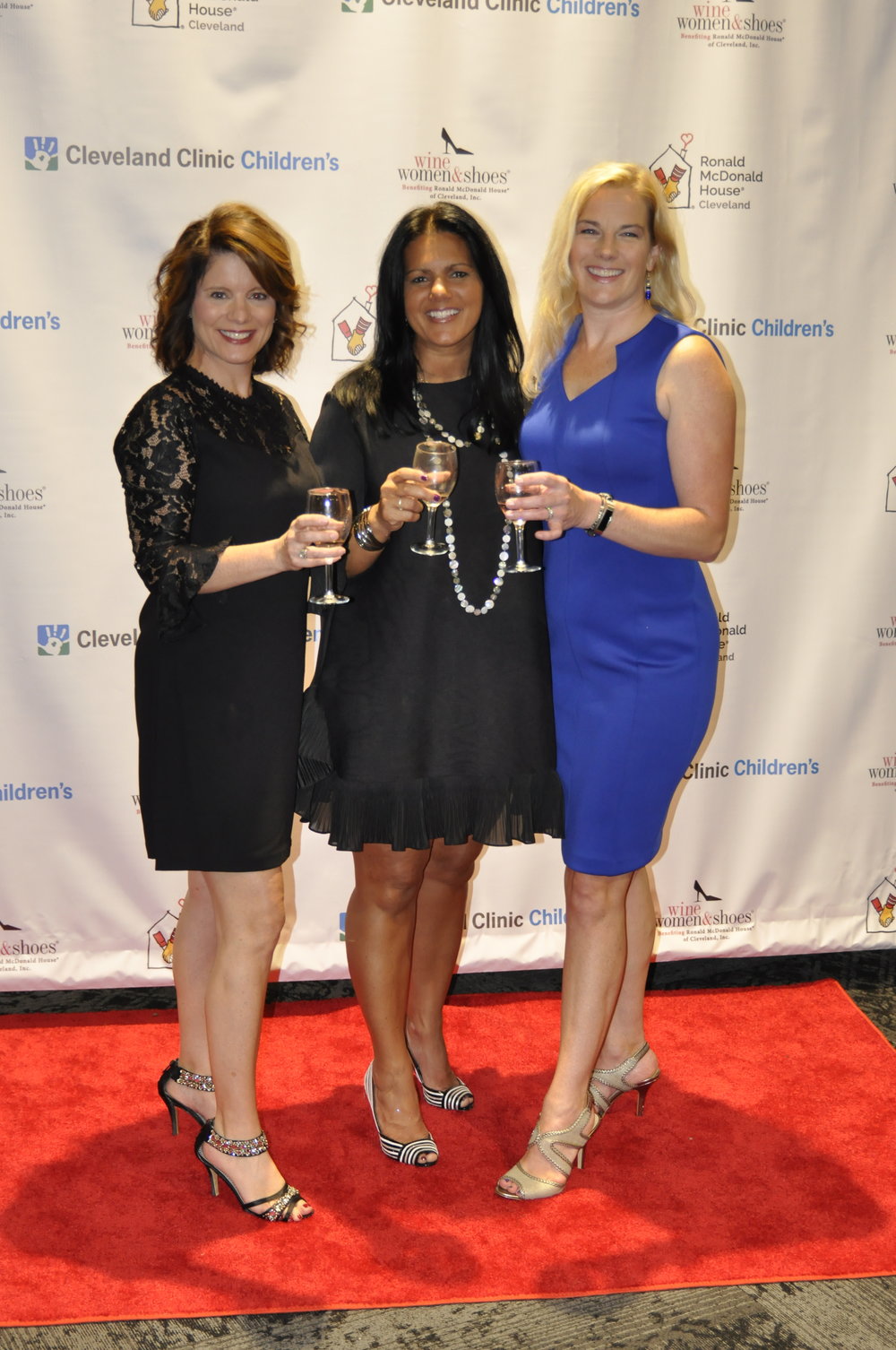 Three women smiling for a photo in front of a backdrop