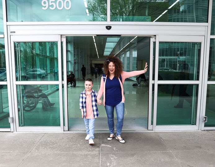 boy and mother holding hands leaving hospital