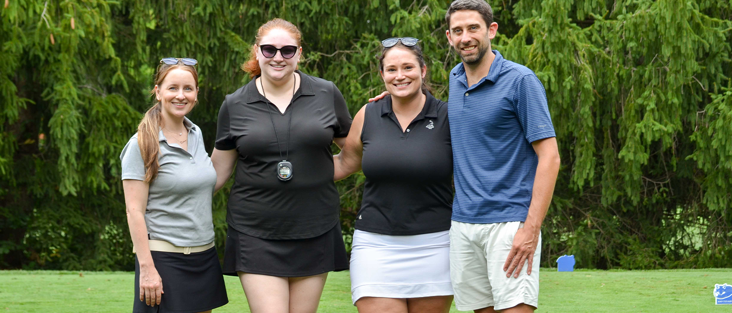Four people pose together on a golf course