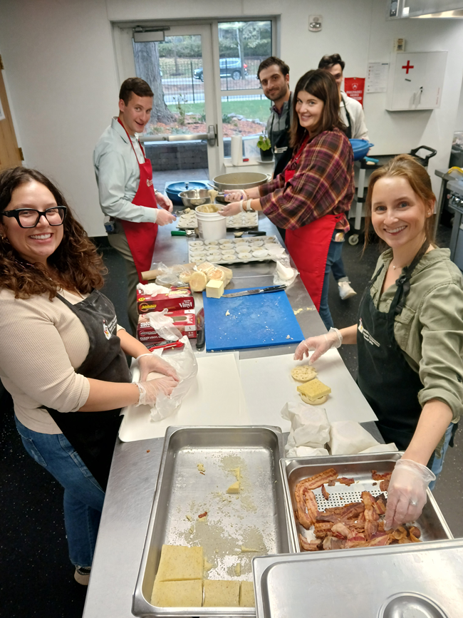 A group of young volunteers preparing and plating a meal together in the House kitchen
