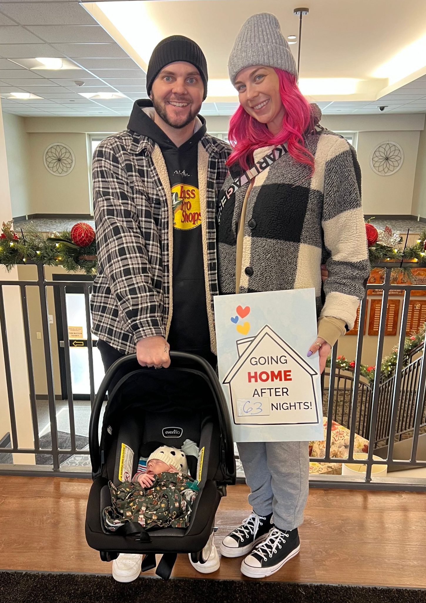 man and woman with baby in carrier with sign