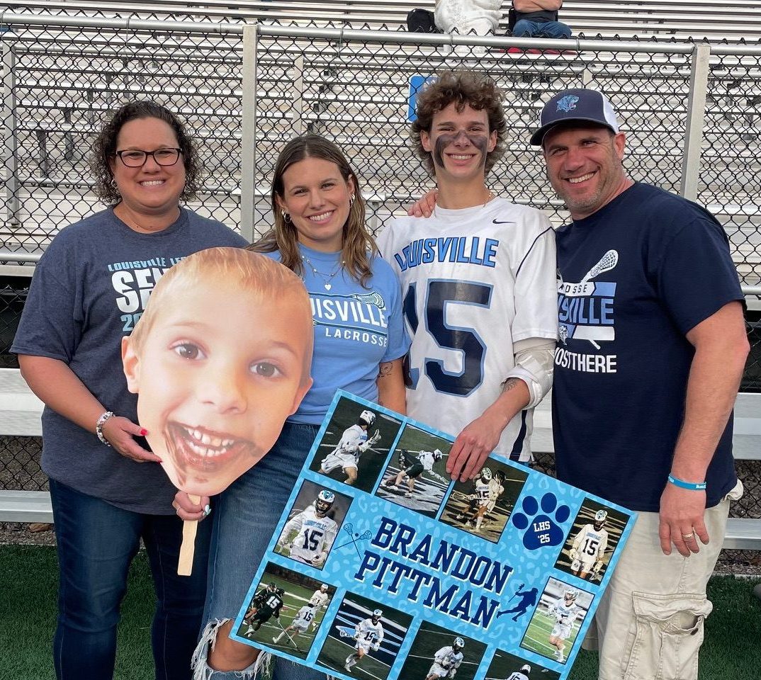 family at lacrosse game with mom, dad, sister, and son.