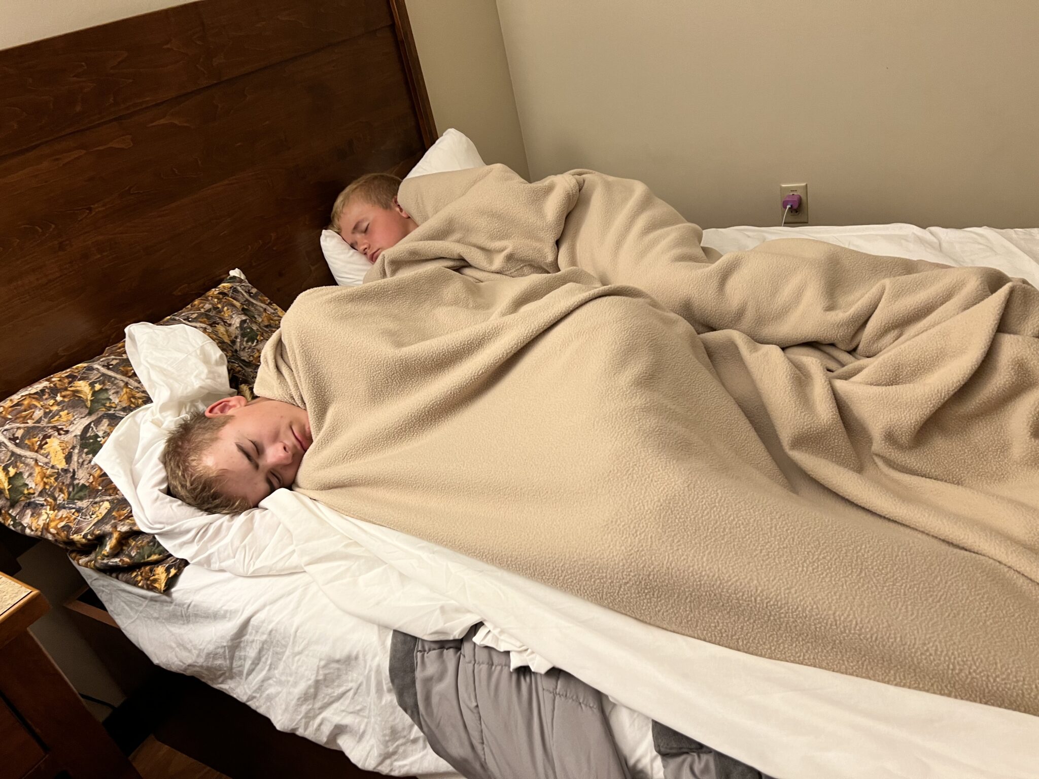Two boys sleeping in bed with blankets
