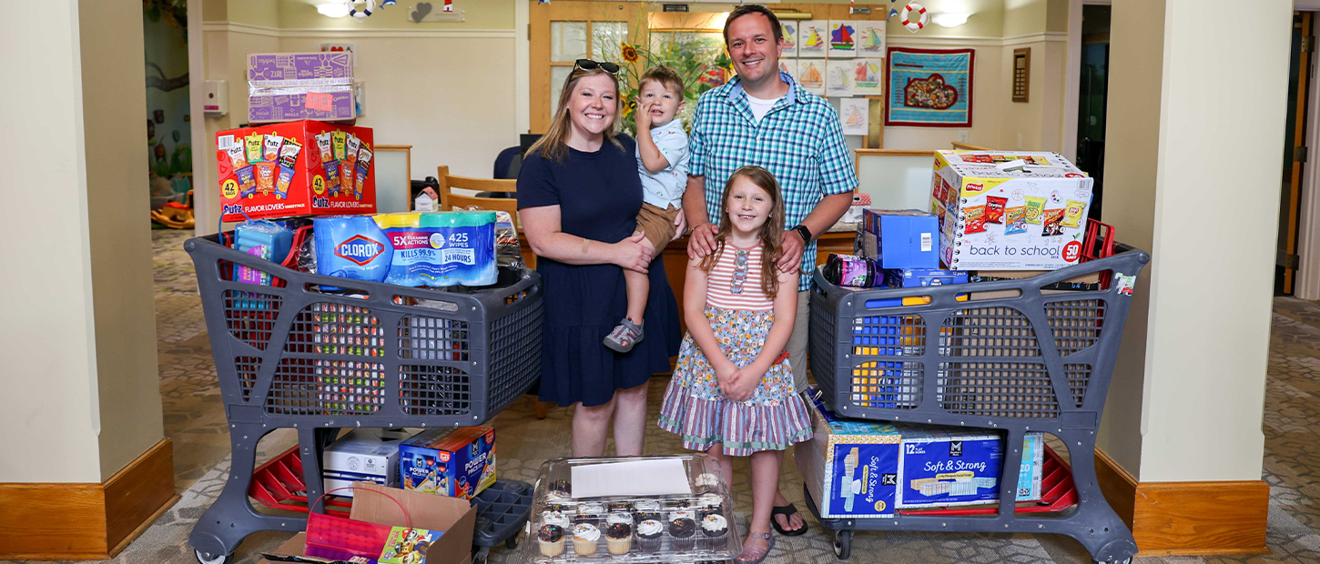 A family stands between two shopping carts filled with donated supplies in a House lobby