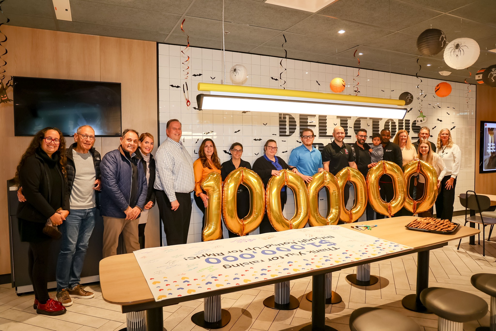 Staff and McDonald's owner-operators stand with gold balloons spelling 1,000,000 beside a banner thanking them for raising $1,000,000 through Round-Up for RMHC