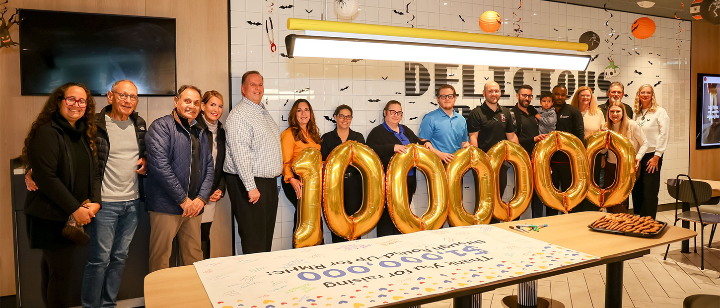 Staff and McDonald's owner-operators stand with gold balloons spelling 1,000,000 beside a banner thanking them for raising $1,000,000 through Round-Up for RMHC