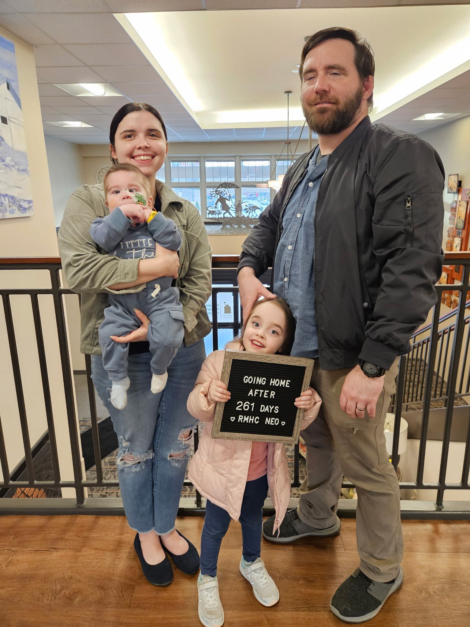 Family of four posing with going home sign.